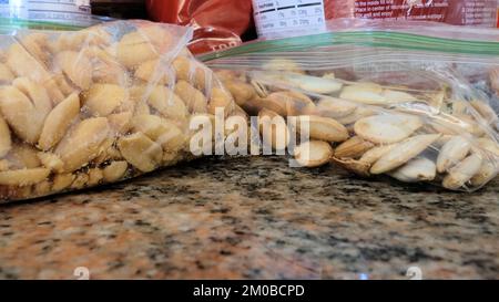 Gros plan de deux sacs en plastique avec arachides salées rôties et graines de citrouille salées rôties sur le comptoir de cuisine emballés pour grignoter, faire de la randonnée, camper. Banque D'Images