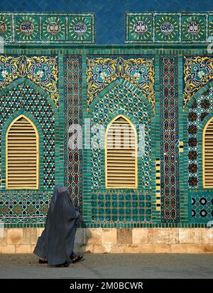 La Mosquée bleue à Mazar-i-Sharif, dans la province de Balkh en Afghanistan. Deux femmes portant des burqas bleus (burkas) marchent le long de la mosquée. Banque D'Images