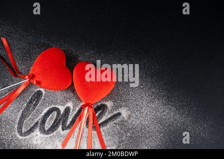 Saint-Valentin, deux coeurs rouges aimant sur fond noir avec des paillettes et le texte de l'amour. Banque D'Images