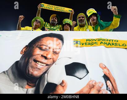 Les fans brésiliens dans les stands au-dessus d'une bannière mettant en vedette l'ancien joueur brésilien Pele avant le match de la coupe du monde de la FIFA, Round of Sixteen, au stade 974 à Doha, au Qatar. Date de la photo: Lundi 5 décembre 2022. Banque D'Images