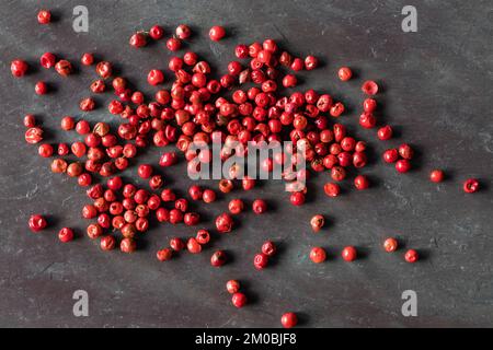 Vue de dessus des grains de poivre rouge sur pierre noire avec espace de copie. Prise de vue macro. Banque D'Images