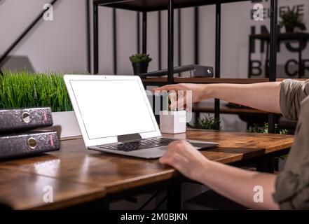 Le doigt pointant, montrant à l'écran vide maquette, modèle d'ordinateur portable dans l'intérieur moderne de bureau. Photo de haute qualité Banque D'Images