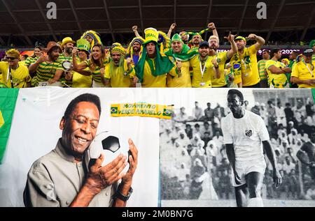 Les fans brésiliens dans les stands au-dessus d'une bannière mettant en vedette l'ancien joueur brésilien Pele avant le match de la coupe du monde de la FIFA, Round of Sixteen, au stade 974 à Doha, au Qatar. Date de la photo: Lundi 5 décembre 2022. Banque D'Images