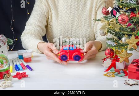 Instructions étape par étape pour faire une décoration de Noël - étape 8 - voiture rouge peinte avec un arbre de Noël. Banque D'Images