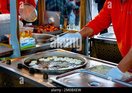 Homme friture le lokma dans l'huile sur un chariot de nourriture de rue. Dessert turc traditionnel ou pâtisserie Lokma ou alias loukoumades en grec. Istanbul Turkiye - 11.10.2 Banque D'Images