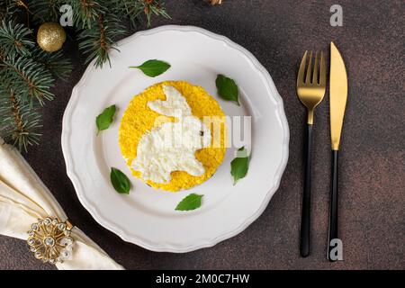 Salade feuilletée Mimosa pour le nouvel an 2023 avec thon en conserve, pommes de terre et carottes, lapin décoré d'œufs, vue du dessus Banque D'Images