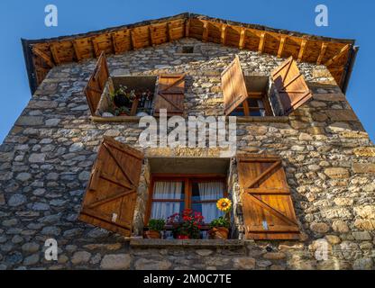 Ancienne maison rurale en pierre dans les Pyrénées avec des fenêtres en bois ouvertes et de précieux pots. La lumière du soleil de fin d'après-midi illumine magnifiquement le vent Banque D'Images