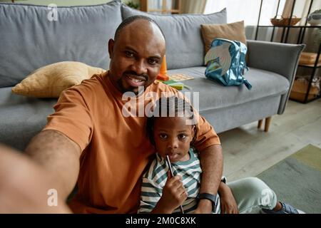Portrait en grand angle de père aimant prenant photo selfie avec fille mignonne dans le cadre de la maison, espace de copie Banque D'Images