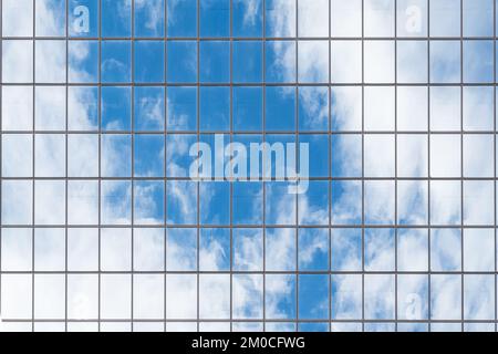 Les nuages et le ciel bleu se reflètent sur un grand gratte-ciel en verre miroir Banque D'Images