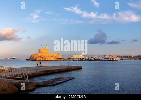 Vue panoramique colorée de la forteresse d'Agios Nikolaos avec yachts dans le port de Mandraki au coucher du soleil, Rhodes Grèce. Photo de haute qualité Banque D'Images