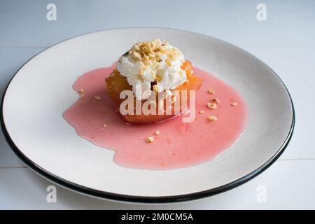 Dessert traditionnel turc de coing, le coing est cuit dans l'eau avec du sucre et servi avec de la crème et de la noisette. Banque D'Images