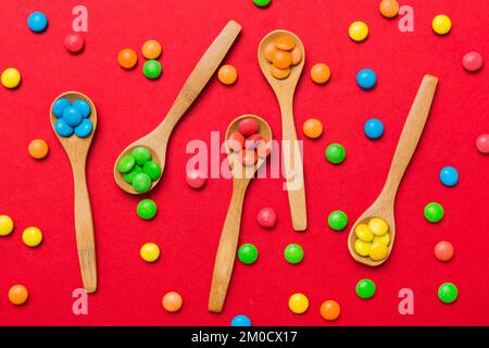 délicieuses sucreries douces colorées sur une cuillère sur fond coloré . Décoration de confiserie, vue de dessus avec espace pour les copies. Banque D'Images