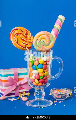 Bonbons colorés dans une tasse sur une table sur fond clair. Grands sucettes tournantes. Concept créatif d'un pot rempli de délicieux bonbons de la Banque D'Images