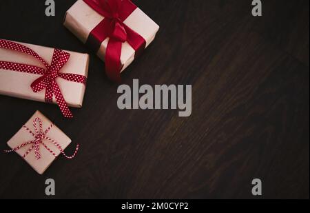 Cadeaux de Noël et cadeaux de vacances traditionnels, boîtes cadeaux de Noël classiques sur fond de bois, cadeau enveloppé dans du papier artisanal avec ruban rouge, style rustique vintage de campagne pour le motif de vacances de saison Banque D'Images