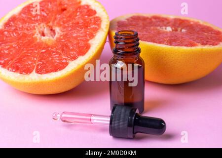 Huile essentielle de pamplemousse avec des bouteilles de pamplemousse frais et de verre brun. avec pipette noire . Banque D'Images