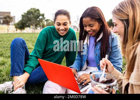 Jeunes étudiantes multiraciales travaillant ensemble sur ordinateur portable sur le campus universitaire Banque D'Images