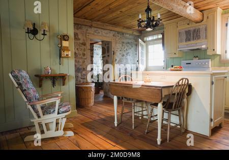 Table de petit-déjeuner antique avec chaises hautes arrondies et meubles dans la cuisine à l'intérieur de la vieille maison de 1722 style cottage Canadiana en pierre de champ. Banque D'Images