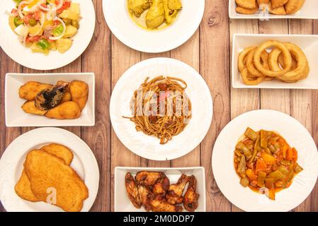 Ensemble de délicieuses recettes de cuisine méditerranéenne avec ailes de poulet frites, mât pané, rondelles d'oignon, salade de pommes de terre et de tomates, boulettes de thon Banque D'Images