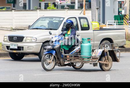 RATCHABURI, THAÏLANDE, NOVEMBRE 16 2022, Une femme dans un tablier conduit une bouteille de gaz sur une moto avec un side-car Banque D'Images