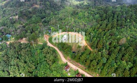 Vue aérienne du drone de route de montagne avec le soleil brille dans la forêt. Vue de dessus d'une route sur une colline dans une belle forêt verte luxuriante en Thaïlande. Naturel Banque D'Images