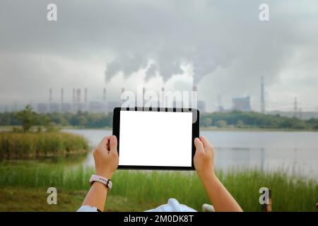 Une femme mécanicien en chef portant un gilet vert et un casque se tient à l'extérieur contre le fond de la centrale au charbon et de vapeur dans la brume matinale. Banque D'Images