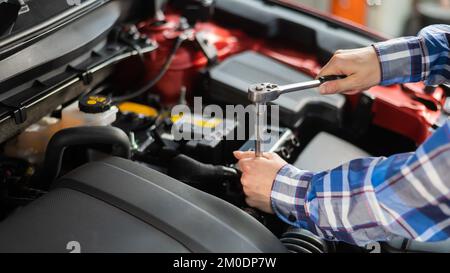 Mécanique automobile femelle en dévissant un écrou pour remplacer une bougie d'allumage de voiture. Banque D'Images