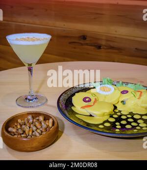 Papa a la huancaina, servi avec des olives, des œufs durs et de la laitue, accompagnés de pisco sour Banque D'Images