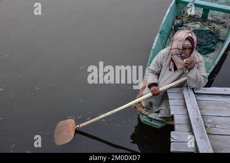 Srinagar, Inde. 05th décembre 2022. Un boatman mange du pain pendant qu'il attend les clients à l'intérieur du lac Dal pendant une matinée froide et brumeuse à Srinagar. Après la baisse des températures, le Cachemire est témoin d'une intense vague de froid et de conditions météorologiques brumeuses. Le météo a prévu un sort humide de deux jours entre 9 décembre et 10 dans la région. Crédit : SOPA Images Limited/Alamy Live News Banque D'Images