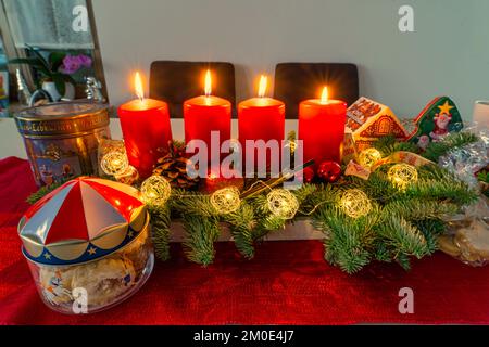 Une couronne d'advents avec quatre bougies allumées et quelques biscuits, temps avant la veille de noël. Banque D'Images