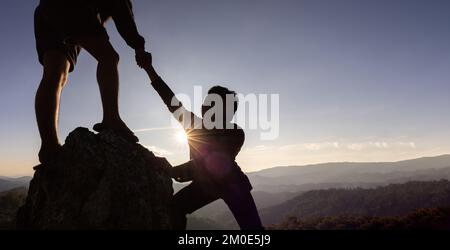 Silhouette de main d'aide entre deux grimpeurs. couple de randonnée aider les uns les autres silhouette dans les montagnes avec la lumière du soleil. Les hommes qui aident à tirer les gens vers le haut fr Banque D'Images