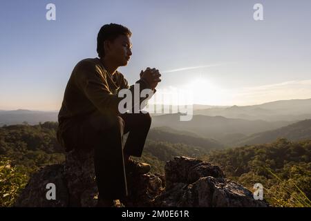 Silhouette. Homme priant à dieu sur la montagne. Priez avec les mains avec la foi en la religion et la croyance en Dieu sur la base de la bénédiction. la puissance de l'espoir ou de l'amour Banque D'Images