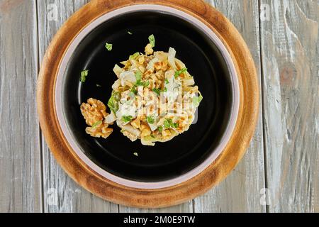 Salade de chicorée endive avec sauce Roquefort sur une assiette noire. Pose à plat. Banque D'Images