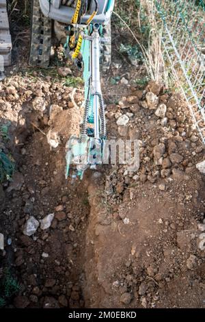 Une minipelle creuse une tranchée pour poser les tuyaux. Gros plan d'une pelle hydraulique creusant une tranchée profonde. Une pelle hydraulique creuse une tranchée dans la campagne pour déposer un Banque D'Images