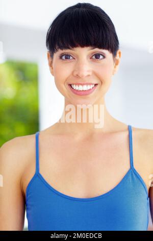 Une touche de fraîcheur et un sourire éclatant. Jolie jeune femme en vêtements d'exercice vous donnant un large sourire. Banque D'Images