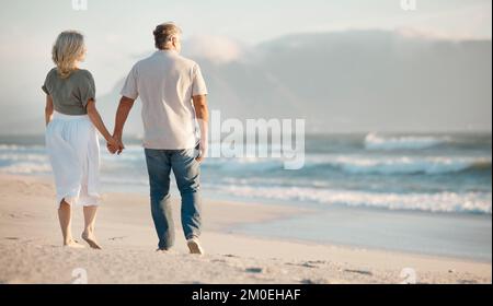 Couple d'âge mûr marchant sur la plage. Arrière du couple senior tenant la main sur les vacances ensemble. Couple d'âge mûr appréciant des vacances au bord de la mer. Senior Banque D'Images