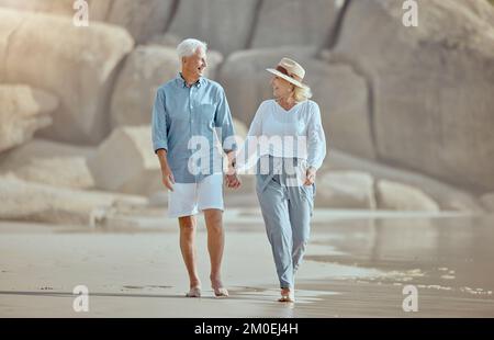 Un heureux couple de caucasiens matures appréciant l'air frais sur les vacances à la plage. Un couple retraité souriant se fait entraîner pour un entraînement cardio-vasculaire tout en marchant à l'extérieur Banque D'Images