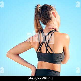 Vision belle femme pratiquant l'exercice de yoga sur la plage. Jeune athlète féminine souffrant de douleurs au cou tout en s'entraîner à l'extérieur. En difficulté Banque D'Images
