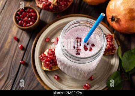 Smoothie aux protéines végétaliennes à base de grenade et de banane sur une table rustique en bois. Une alimentation saine, un mode de vie sain. Foodism, régime alimentaire cru. Banque D'Images