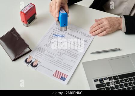 Gros plan d'un travailleur méconnaissable portant un timbre approuvé sur le formulaire de demande de visa au bureau d'immigration des États-Unis Banque D'Images