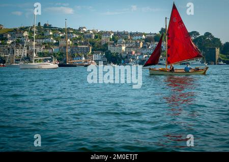 22nd juillet 2021 - Fowey, Royaume-Uni: La vue d'un voyage en bateau autour du port à Fowey, Cornwall et la magnifique voile rouge sur un petit bateau passant. En regardant vers Polruan. Banque D'Images