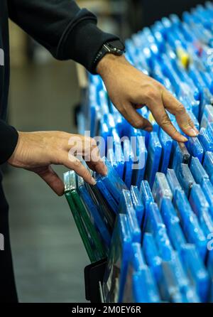 Les mains recherchant et choisissant des films et des dvd sur une étagère dans un magasin de collectionneur de film et la vente de marchandises de disques de film Banque D'Images