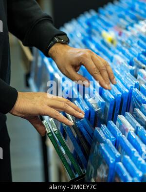 Les mains recherchant et choisissant des films et des dvd sur une étagère dans un magasin de collectionneur de film et la vente de marchandises de disques de film Banque D'Images