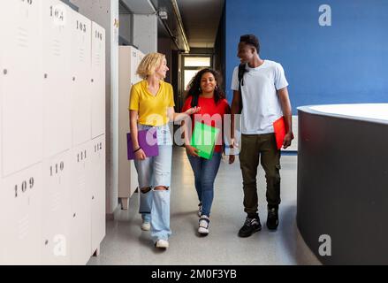 Groupe multiethnique de jeunes élèves qui parlent après des cours au secondaire Banque D'Images