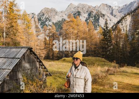 Portrait d'une jeune femme marchant sur un pré avec des mélèzes dorés sous les montagnes au col de Vrsic moutnain en Slovénie Banque D'Images