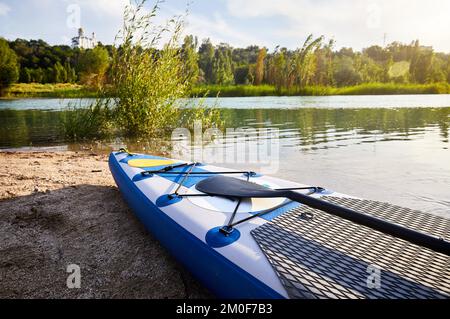 Montez des planches à aubes SUP sur la plage dans le lac de montagne Sairan dans la ville d'Almaty près de l'église orthodoxe au Kazakhstan. Banque D'Images