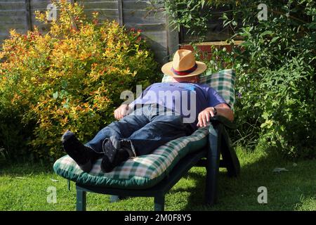 Vieil homme ou homme âgé allongé sur un fauteuil inclinable au soleil et reposant. Banque D'Images