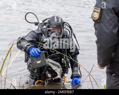 Manching, Allemagne. 06th décembre 2022. Un plongeur de police remet un objet trouvé qu'il a trouvé dans l'étang de Pichler près du Musée celtique à un collègue. L'action de recherche a eu lieu au cours de l'enquête après le vol du Trésor d'or au Musée celtique. Au cours d'une visite au Musée romain celtique de Manching, en haute-Bavière, un Trésor d'or pesant plusieurs kilos avait été volé, composé principalement de pièces de monnaie. Credit: Peter Kneffel/dpa/Alay Live News Banque D'Images