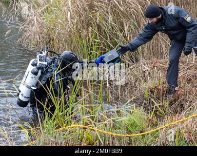 Manching, Allemagne. 06th décembre 2022. Un plongeur de police passe un objet trouvé à un collègue, qu'il avait précédemment trouvé du Pichler Weiher près du Musée celtique. L'action de recherche a eu lieu au cours de l'enquête après le vol du Trésor d'or au Musée celtique. Au cours d'une visite au Musée romain celtique de Manching, en haute-Bavière, un Trésor d'or pesant plusieurs kilos avait été volé, composé principalement de pièces de monnaie. Credit: Peter Kneffel/dpa/Alay Live News Banque D'Images