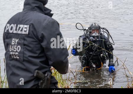 Manching, Allemagne. 06th décembre 2022. Un plongeur de police remet un objet trouvé qu'il a trouvé dans l'étang de Pichler près du Musée celtique à un collègue. L'action de recherche a eu lieu au cours de l'enquête après le vol du Trésor d'or au Musée celtique. Au cours d'une visite au Musée romain celtique de Manching, en haute-Bavière, un Trésor d'or pesant plusieurs kilos avait été volé, composé principalement de pièces de monnaie. Credit: Peter Kneffel/dpa/Alay Live News Banque D'Images