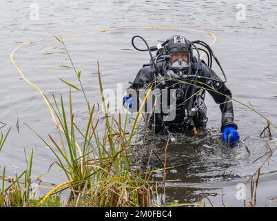 Manching, Allemagne. 06th décembre 2022. Un plongeur de police porte un objet trouvé hors de l'eau, qu'il a trouvé plus tôt dans l'étang de Pichler près du Musée celtique. L'action de recherche a eu lieu au cours de l'enquête après le vol du Trésor d'or au Musée celtique. Au cours d'une visite au Musée romain celtique de Manching, en haute-Bavière, un Trésor d'or pesant plusieurs kilos avait été volé, composé principalement de pièces de monnaie. Credit: Peter Kneffel/dpa/Alay Live News Banque D'Images